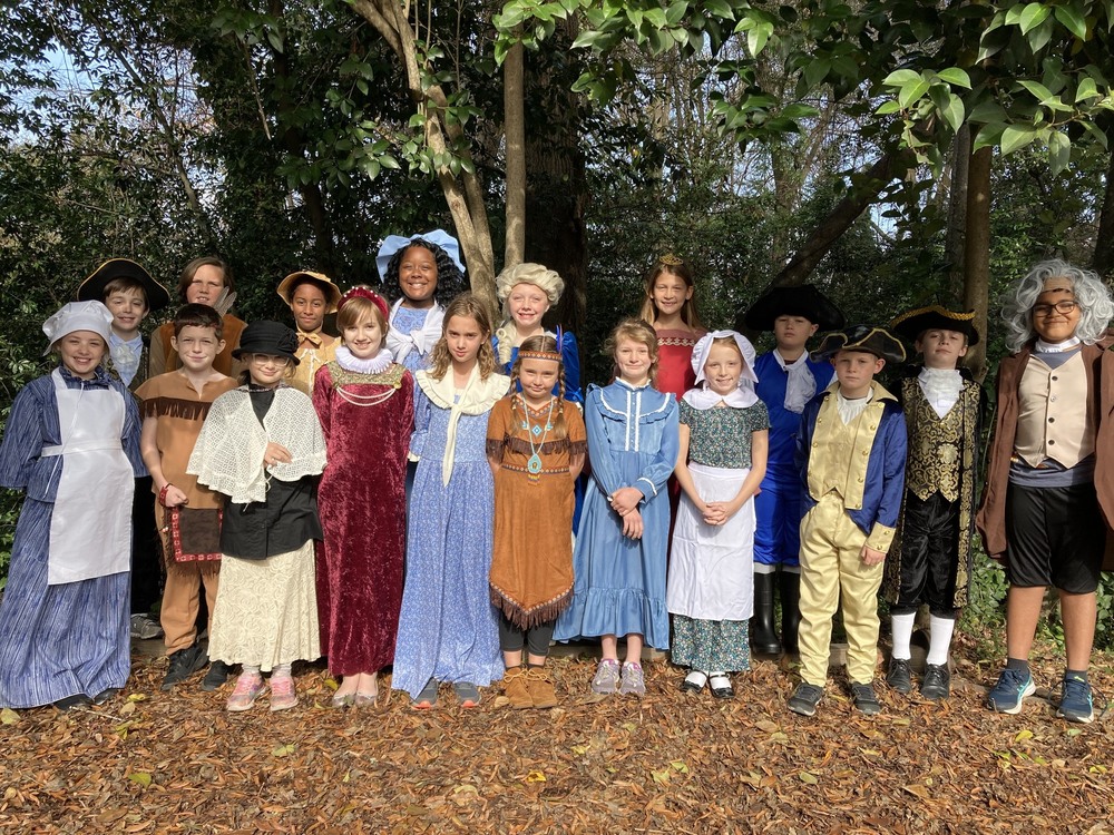 A group of children outdoors, dressed as historical figures
