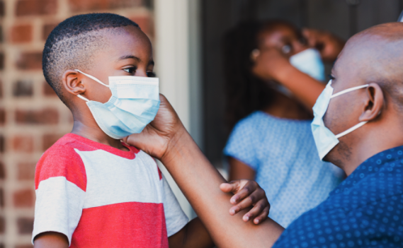 A teacher assisting a student with his mask